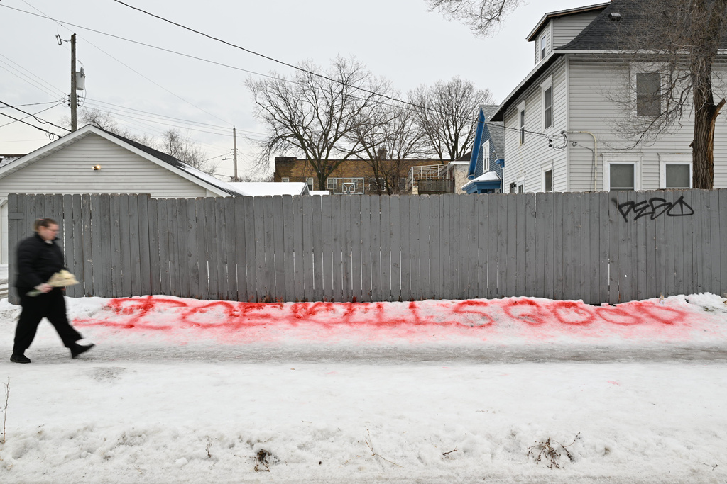 A person walks by writing in the snow near a makeshift memorial honoring the victim of a fatal shooting involving federal law enforcement agents, near the site of the shooting, Thursday, Jan. 8, 2026, in Minneapolis. (AP Photo/Tom Baker)