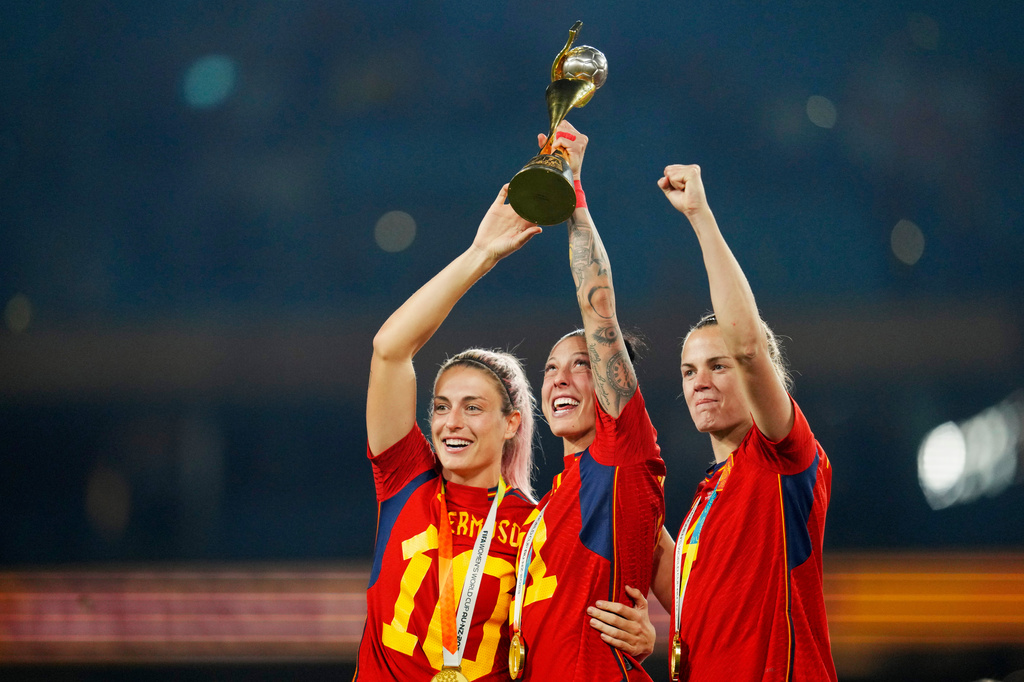 FILE - Spain's Alexia Putellas, Jennifer Hermoso and Irene Paredes ,from left, celebrate with the trophy at the end of the Women's World Cup soccer final between Spain and England at Stadium Australia in Sydney, Australia, Aug. 20, 2023. (AP Photo/Abbie Parr, File)
