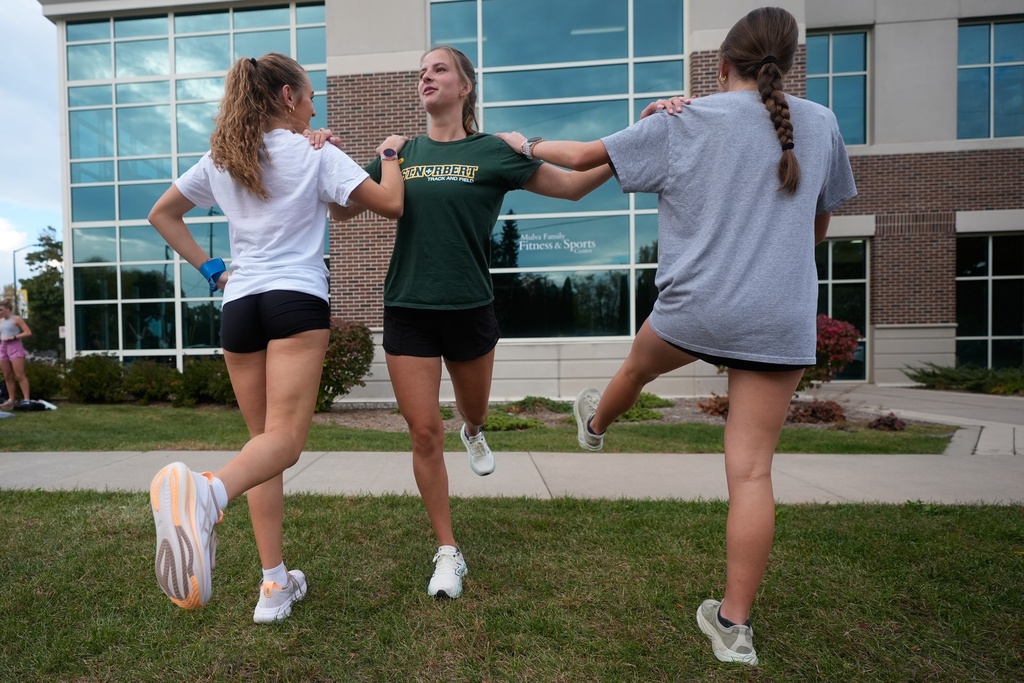 Cross country runner Madison DeCleene warms up with her St. Norbert College teammates, Friday, Oct. 17, 2025, in De Pere, Wis. (AP Photo/Morry Gash)