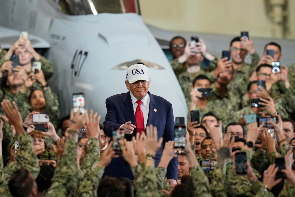U.S. soldiers wave and take smartphones photos of President Donald Trump as he arrives to the aircraft carrier USS George Washington at the U.S. Navy's Yokosuka base, in Yokosuka, south of Tokyo, Tuesday, Oct. 28, 2025. (AP Photo/Eugene Hoshiko)