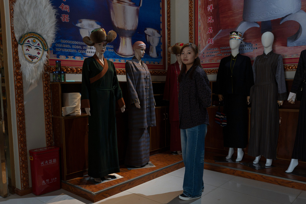 A worker stands near products of the Ethnic Huaji Handwoven Cooperative displayed in a showroom in Shannan in western China's Tibet Autonomous Region on July 23, 2026, as seen during a government organized visit for foreign journalists. (AP Photo/Ng Han Guan)