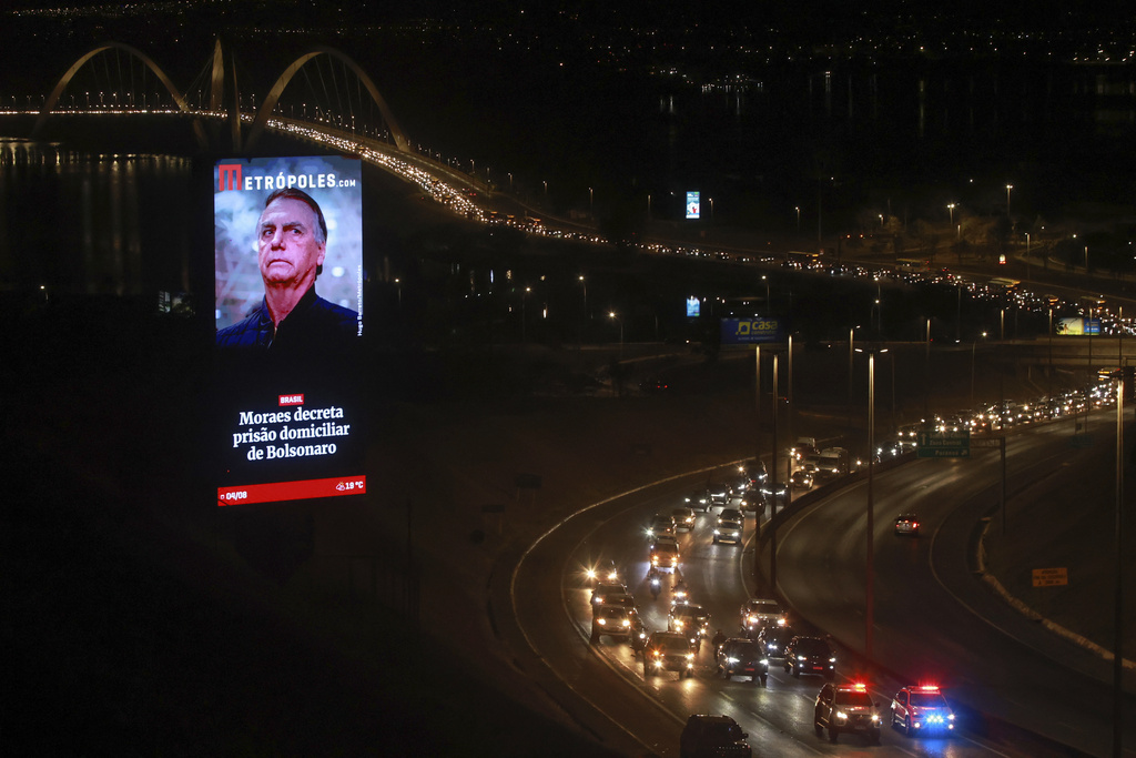 FILE - An electronic billboard with an image of President Jair Bolsonaro and text that reads in Portuguese: "Moraes orders house arrest for Bolsonaro," towers over a caravan of supporters protesting the house arrest order, in Brasilia, Brazil, Aug. 4, 2025. (AP Photo/Luis Nova, File)