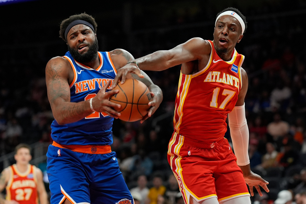 New York Knicks center Karl-Anthony Towns (32) and Atlanta Hawks forward Onyeka Okongwu (17) vie for a loose ball during the first half of an NBA basketball game, Saturday, Dec. 27, 2025, in Atlanta. (AP Photo/Mike Stewart)
