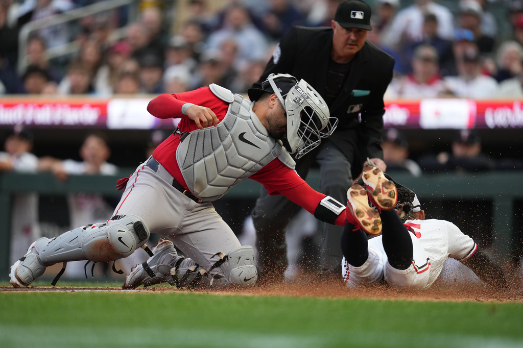 Minnesota Twins' Byron Buxton (25) beats the tag by Boston Red Sox catcher Carlos Narváez (75) to score during the first inning of a baseball game Tuesday, April 14, 2026, in Minneapolis. (AP Photo/Abbie Parr)