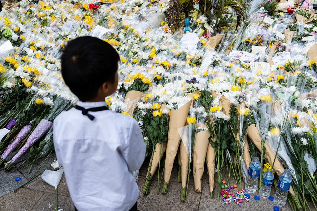 People offer flowers for the victims near the site of a deadly fire at Wang Fuk Court, a residential estate in the Tai Po district of Hong Kong's New Territories on Tuesday, Dec 2, 2025. (AP Photo/Chan Long Hei)