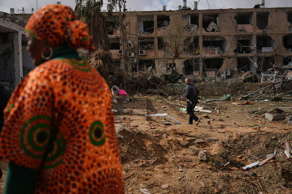 People survey a site that was struck by an Iranian missile in Dimona, southern Israel, Sunday, March 22, 2026. (AP Photo/Ariel Schalit)