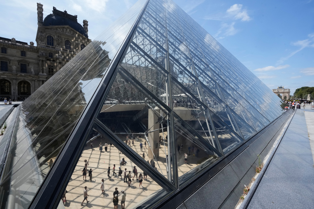 Visitors walks inside the pyramid during the reopening to the public of the Apollo Gallery, at the Louvre museum in Paris, Wednesday, July 22, 2026. (AP Photo/Michel Euler)