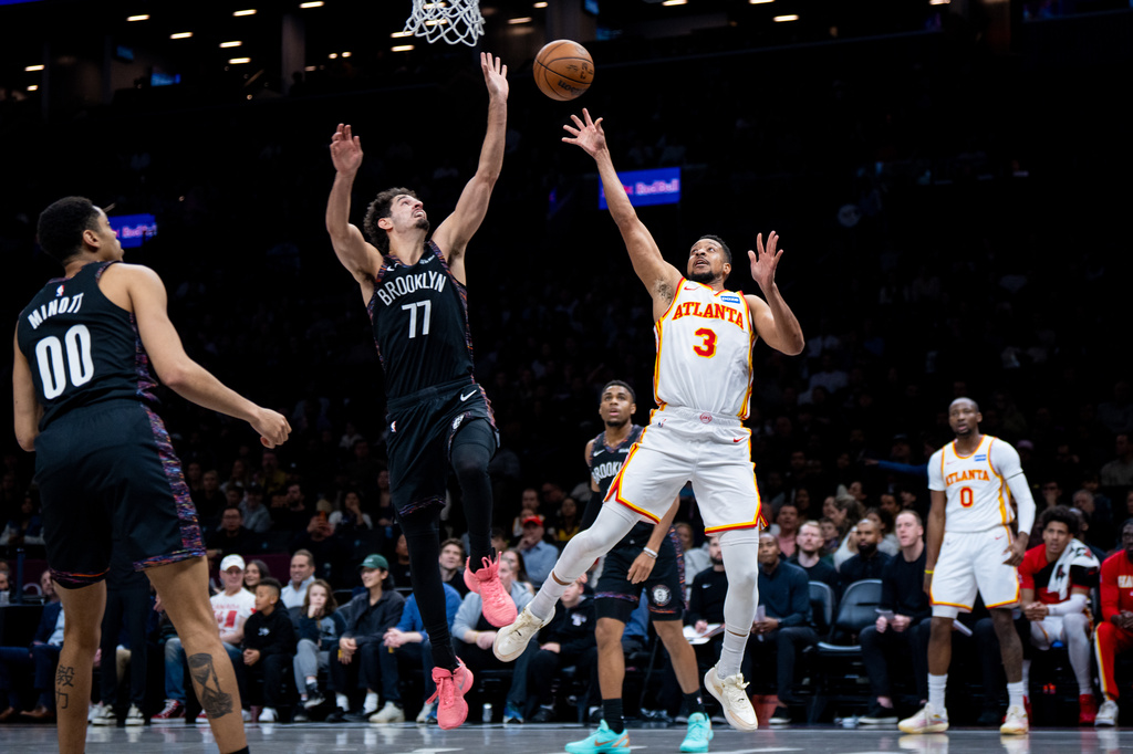Atlanta Hawks guard CJ McCollum (3), defended by Brooklyn Nets guard Ben Saraf (77), shoots a two-pointer during the first half of an NBA basketball game, Friday, April 3, 2026, in New York. (AP Photo/Angelina Katsanis)