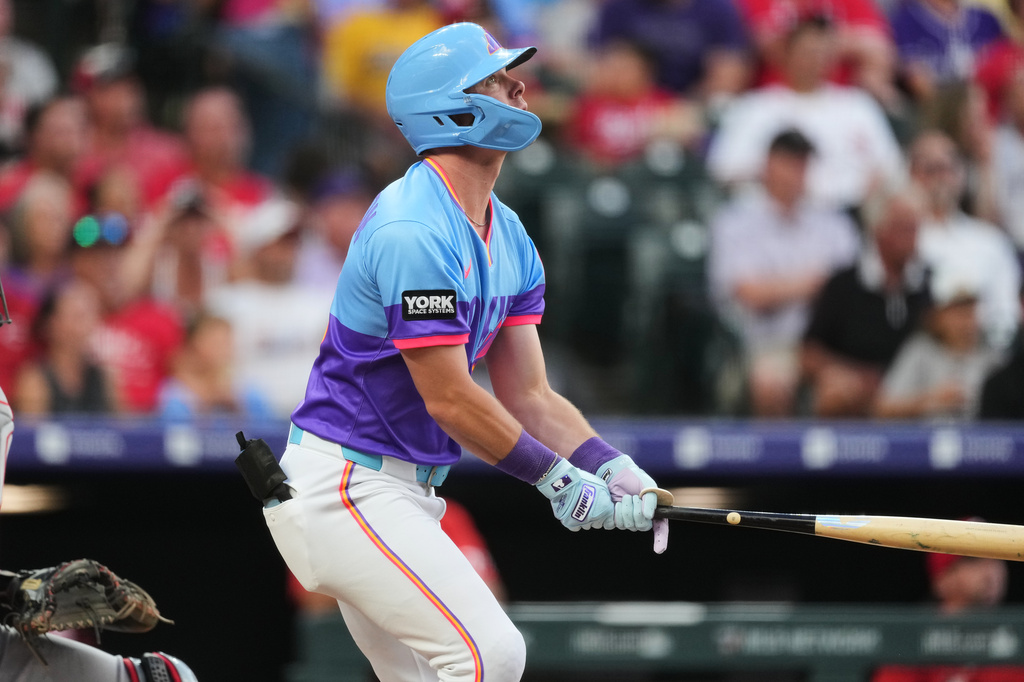 Colorado Rockies' Troy Johnston follows the flight of his sacrifice fly to drive in a run against Cincinnati Reds starting pitcher Brady Singer in the fifth inning of a baseball game Friday, July 17, 2026, in Denver. (AP Photo/David Zalubowski)