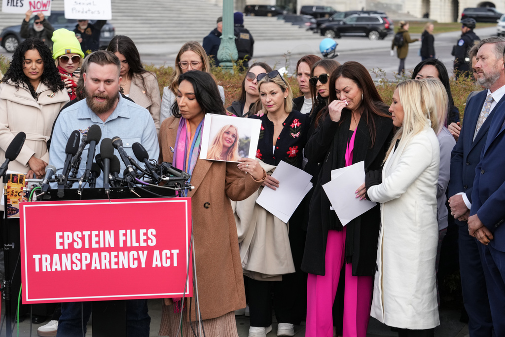 Sky Roberts, brother of prominent Epstein accuser Virginia Giuffre, speaks as his wife Amanda holds her photograph during a news conference as the House prepares to vote on the Epstein Files Transparency Act, at the Capitol in Washington, Tuesday, Nov. 18, 2025. Rep. Marjorie Taylor-Greene, R-Ga., and Rep. Thomas Massie, R-Ky., listen at right. (AP Photo/J. Scott Applewhite)