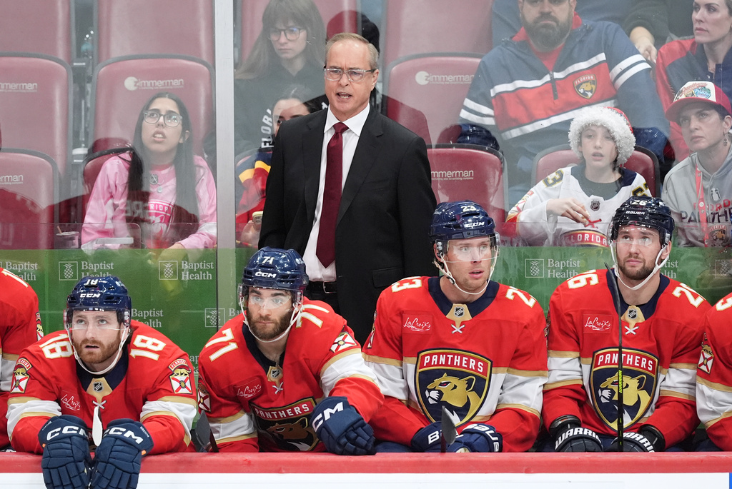 Florida Panthers head coach Paul Maurice stands behind players left wing Noah Gregor (18), center Luke Kunin (71), center Carter Verhaeghe (23), and defenseman Uvis Balinskis (26) during the third period of an NHL hockey game against the Calgary Flames, Friday, Nov. 28, 2025, in Sunrise, Fla. (AP Photo/Rebecca Blackwell)