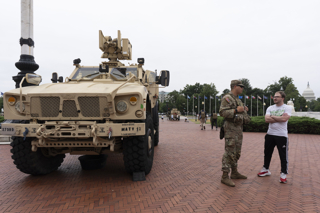 A member of the District of Columbia Army National Guard, talks to passerby Truman Horn, right of Nebraska next to an M-ATV infantry mobility vehicle, outside the Union Station in Washington, Monday, Aug. 18, 2025. (AP Photo/Manuel Balce Ceneta)