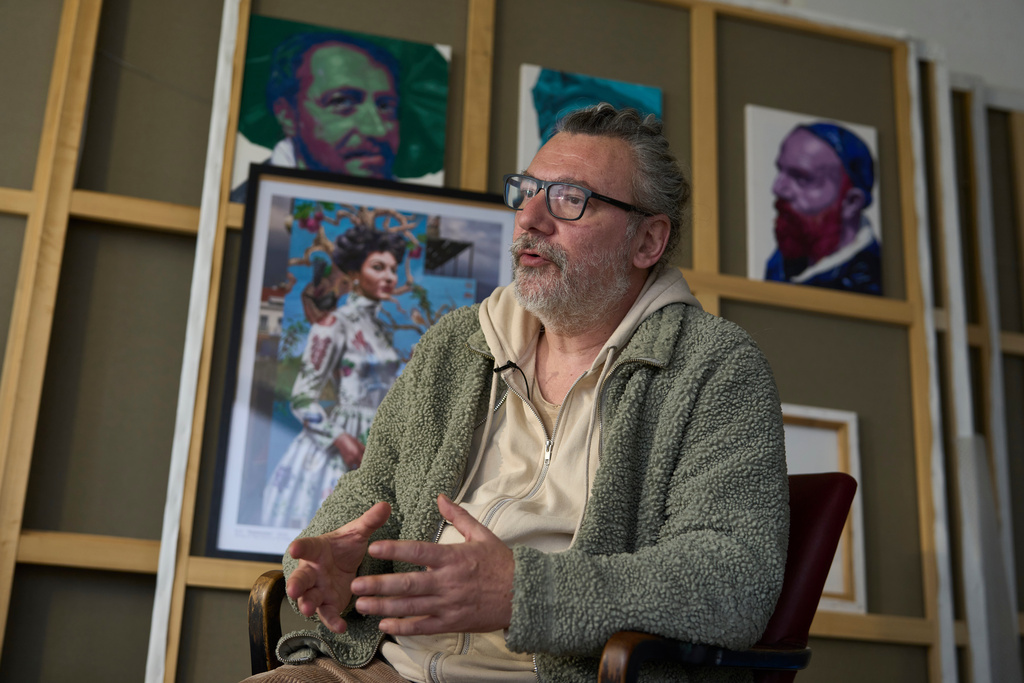 Artist Kleomenis Kostopoulos speaks to The Associated Press in front of a poster with the mural he created depicting opera legend Maria Callas inside his workshop in Patras city about 215 kilometres (134 miles) west of Athens, Tuesday, Feb. 10, 2026. (AP Photo/Petros Giannakouris)