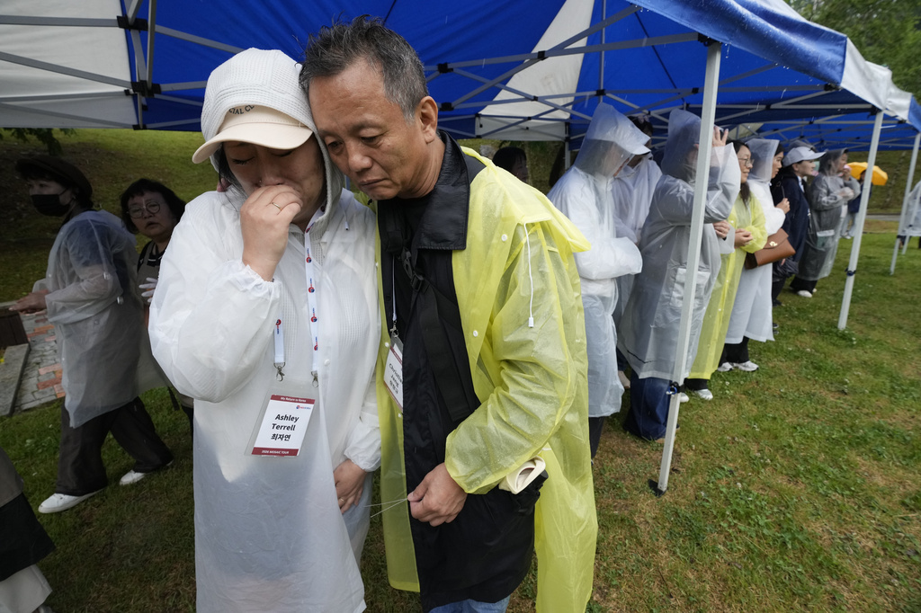 Ashley E. Terrell, left, a Korean adoptee from the United States and Christian Jang-Mikkelsen, a Korean adoptee from Denmark, embrace after hanging their nametags at The Wall of Names at Omma Poom Park in Paju, South Korea, on May 20, 2026. (AP Photo/Ahn Young-joon)