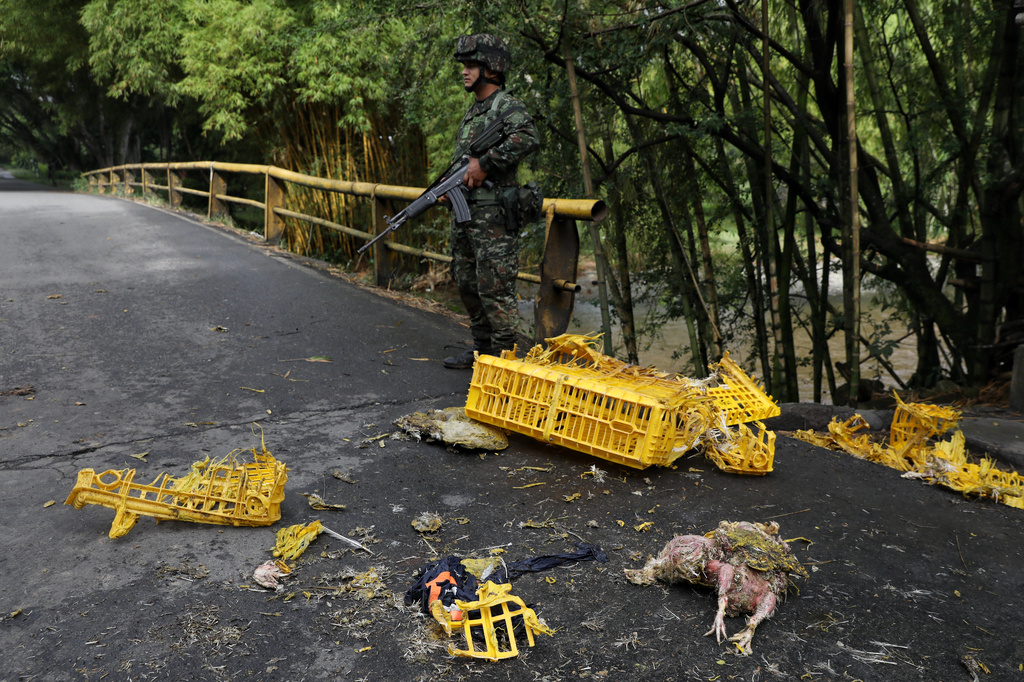 Soldiers stand next to a truck carrying chickens that was set on fire by dissident factions of the former FARC rebels in Jamundi, Colombia, Monday, April 27, 2026. (AP Photo/Santiago Saldarriaga)