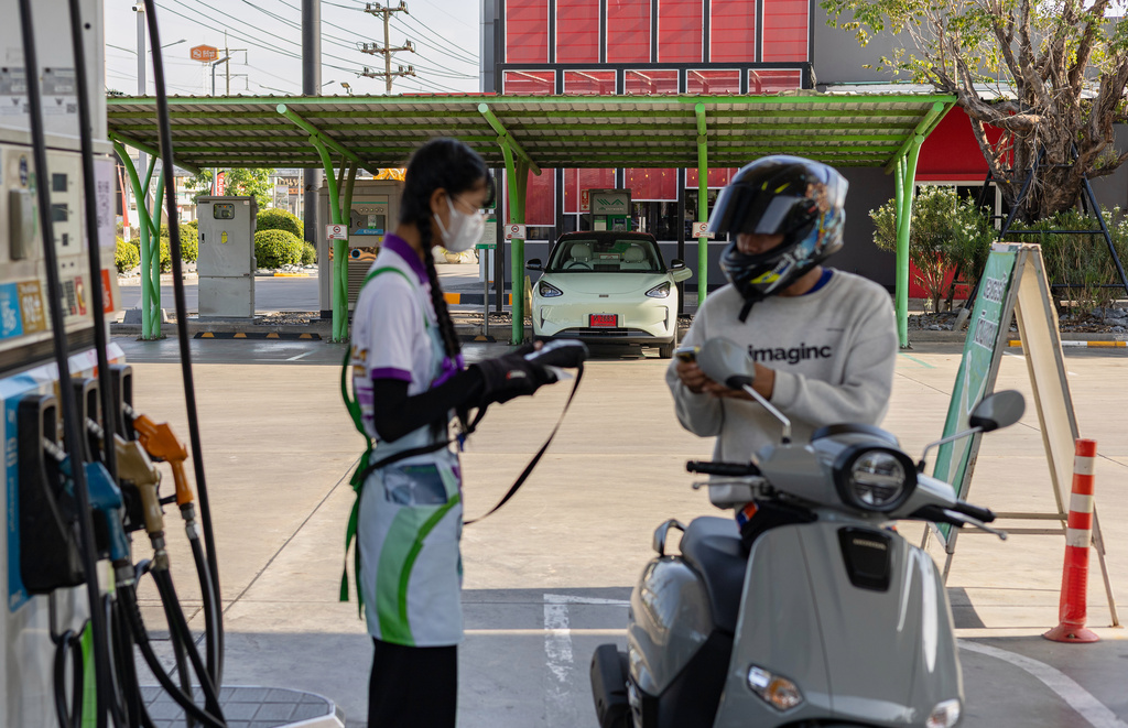 A motorcyclist fills his tank in front of an electric vehicle charging terminal at a gas station in Thailand's Nakorn Pathom province on May 28, 2026. (AP Photo/Anton L. Delgado)