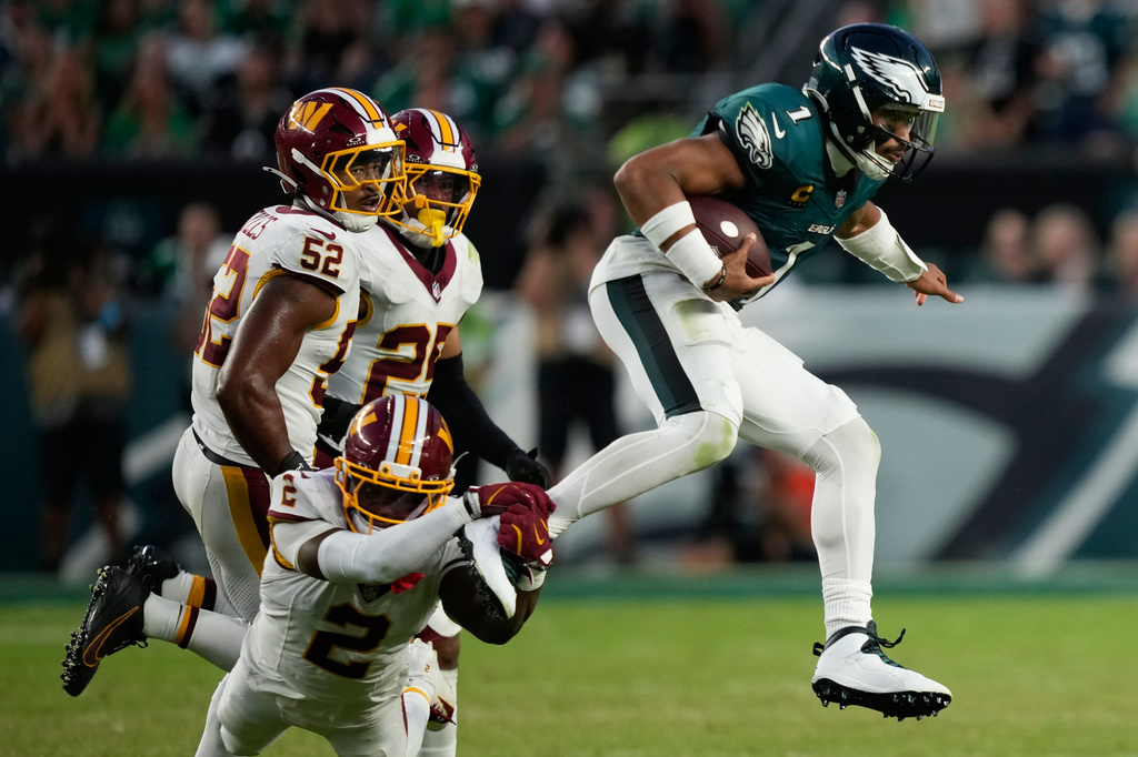 Philadelphia Eagles quarterback Jalen Hurts (1) is grabbed by Washington Commanders cornerback Amik Robertson (2) as he scramble during the second half of an NFL football game, Sunday, Sept. 13, 2026, in Philadelphia. (AP Photo/Matt Slocum)