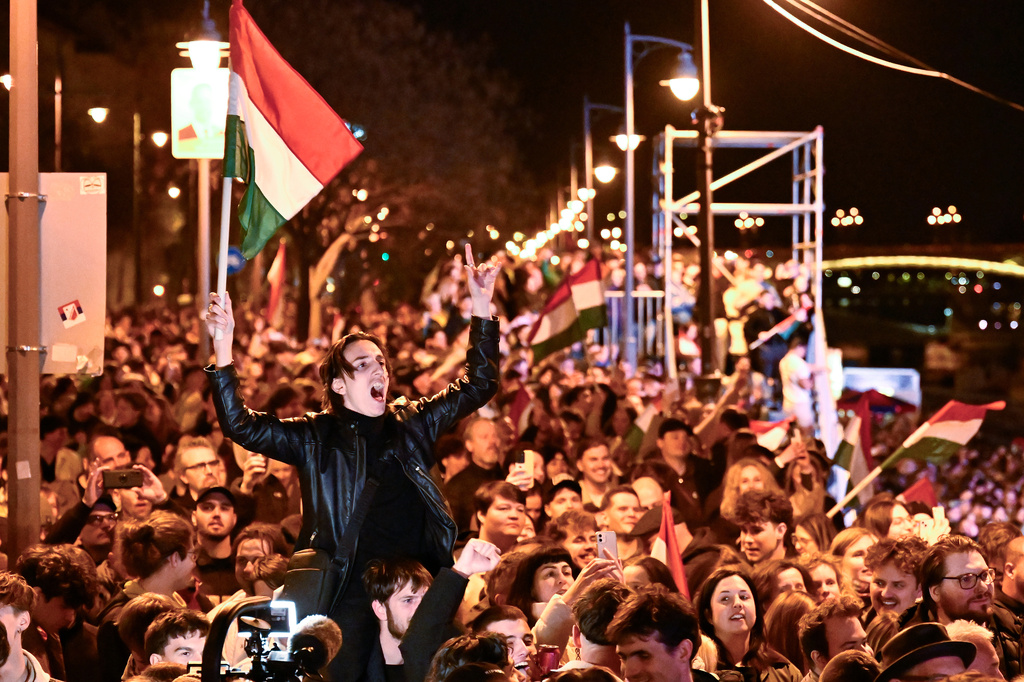 A man waves a Hungarian flag as he celebrates in the streets after the announcement of partial results of the Hungarian parliamentary election in Budapest, Hungary, Sunday, April 12, 2026. (AP Photo/Denes Erdos)