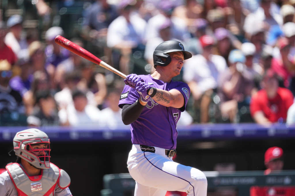 Colorado Rockies' TJ Rumfield follows the flight of his RBI single off Cincinnati Reds starting pitcher Rhett Lowder in the second inning of a baseball game Saturday, July 18, 2026, in Denver. (AP Photo/David Zalubowski)