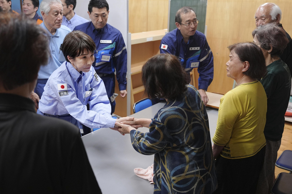 Japan's Prime Minister Sanae Takaichi, center left, greets evacuees as she visits an evacuation center in Hikawa, southern Japan, Monday, Aug. 3, 2026. (Japan Pool/Kyodo News via AP)