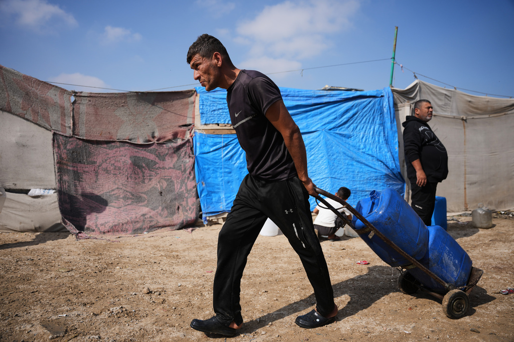 A Palestinian man carries jerrycans filled with water through a tent camp in Khan Younis, in the southern Gaza Strip, Thursday, April 30, 2026. (AP Photo/Abdel Kareem Hana)