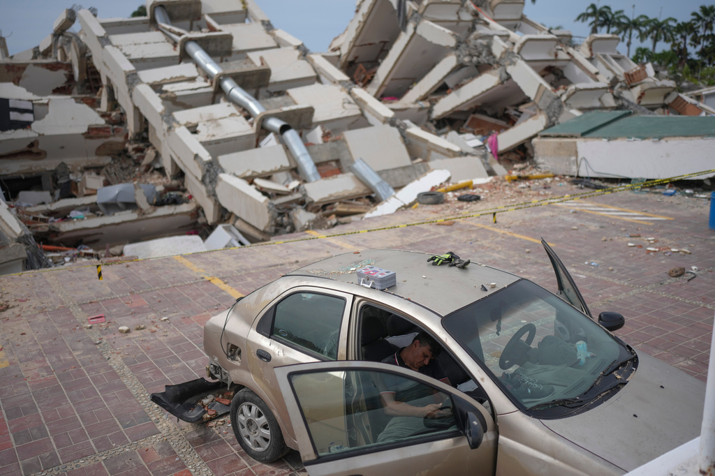 A volunteer helping remove debris from buildings damaged by the earthquakes rests on a damaged car in La Guaira, Venezuela, Friday, July 3, 2026. (AP Photo/Matias Delacroix)