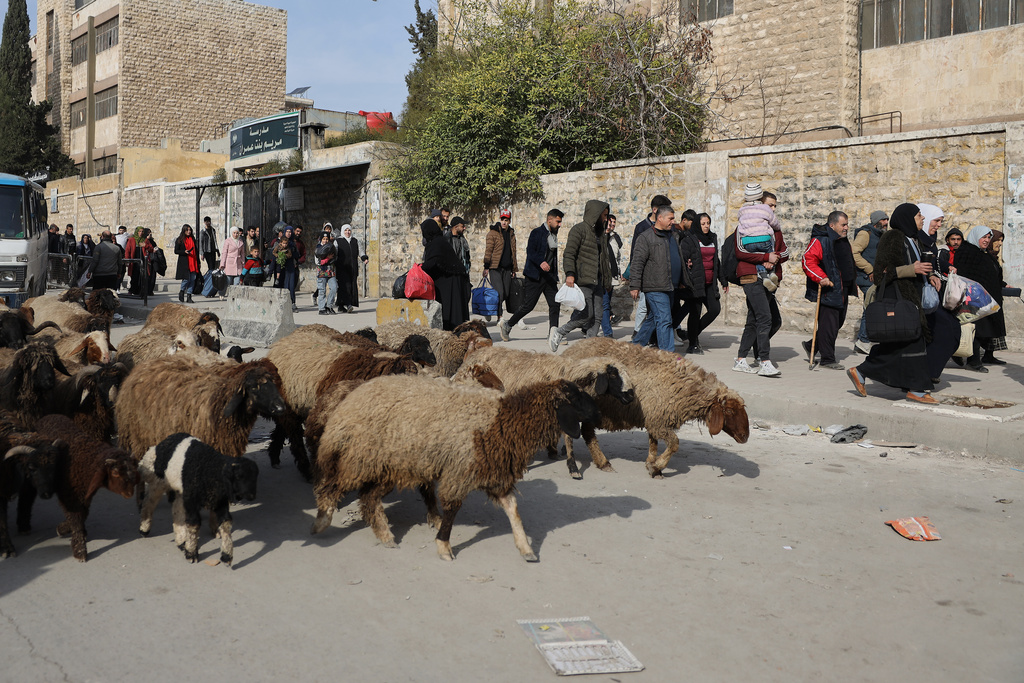 Residents carry their belongings, as they are fleeing from Sheikh Maqsoud and Achrafieh neighborhoods after clashes broke out on Tuesday between Syrian government forces and Kurdish fighters in a contested area of the northern city of Aleppo, Syria, Wednesday, Jan. 7, 2026. (AP Photo/Omar Albam)