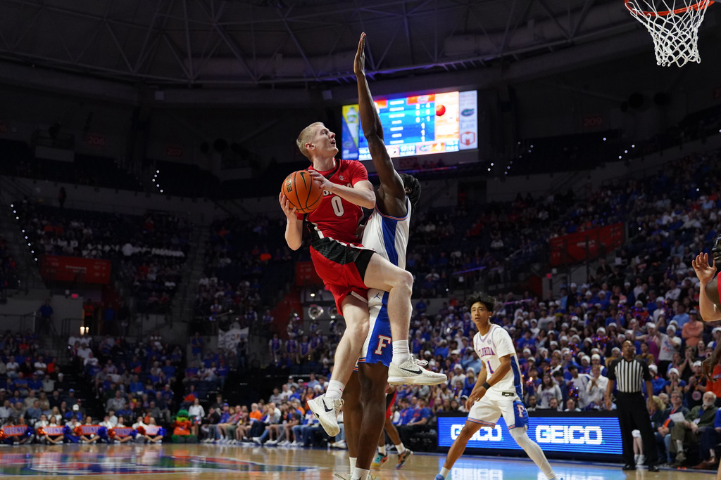 Georgia guard Blue Cain jumps to dunk the ball as Florida center Rueben Chinyelu attempts to block during the first half of an NCAA college basketball game Tuesday, Jan. 6, 2026, in Gainesville, Fla. (AP Photo/Morgan Hurd)