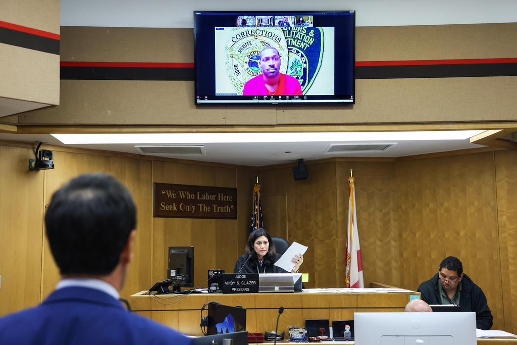 Former NFL star wide receiver Antonio Brown, on monitor above, appears for his bond hearing via video after his attorney Mark Eiglarsh, left, filed a written plea of "not guilty" for an attempted murder charge as Judge Mindy S. Glazer presides, Wednesday, Nov. 12, 2025, in Miami. (Carl Juste/Miami Herald via AP, Pool)