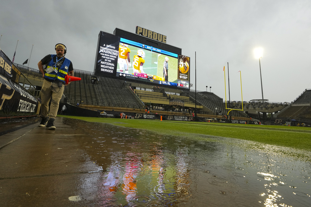 A member of the television crew walks down the sideline as severe weather delay the start of an NCAA college football game between Purdue and Southern California in West Lafayette, Ind., Saturday, Sept. 13, 2025. (AP Photo/Michael Conroy)