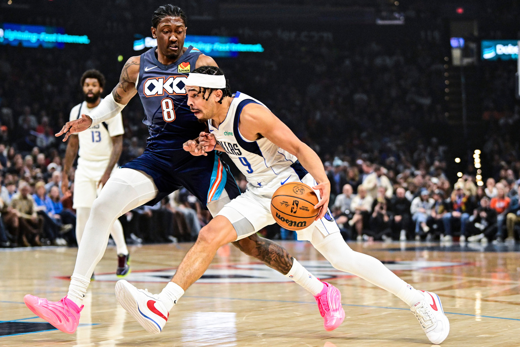Dallas Mavericks guard Ryan Nembhard (9) drives against Oklahoma City Thunder guard/forward Jalen Williams (8) during the first half of an NBA basketball game, Friday, Dec. 5, 2025, in Oklahoma City. (AP Photo/Gerald Leong)