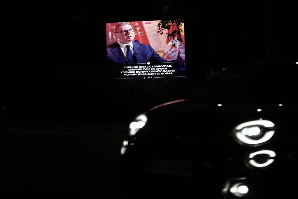 A car passes by a big screen showing Serbian President Aleksandar Vucic, reading: " I am too stubborn. I am too much of a Serb. I love Serbia too much to be to the taste of the power mongers." before his opponents first big rally this year in Belgrade, Serbia, Tuesday, May 19, 2026. (AP Photo/Darko Vojinovic)