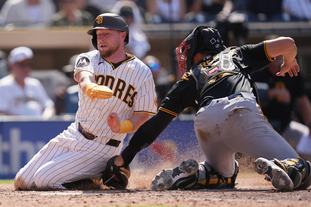San Diego Padres' Jake Cronenworth, left, is tagged out by Pittsburgh Pirates catcher Rafael Flores Jr., trying to score from second base off a single by Manny Machado during the eighth inning of a baseball game Wednesday, Aug. 26, 2026, in San Diego. (AP Photo/Gregory Bull)