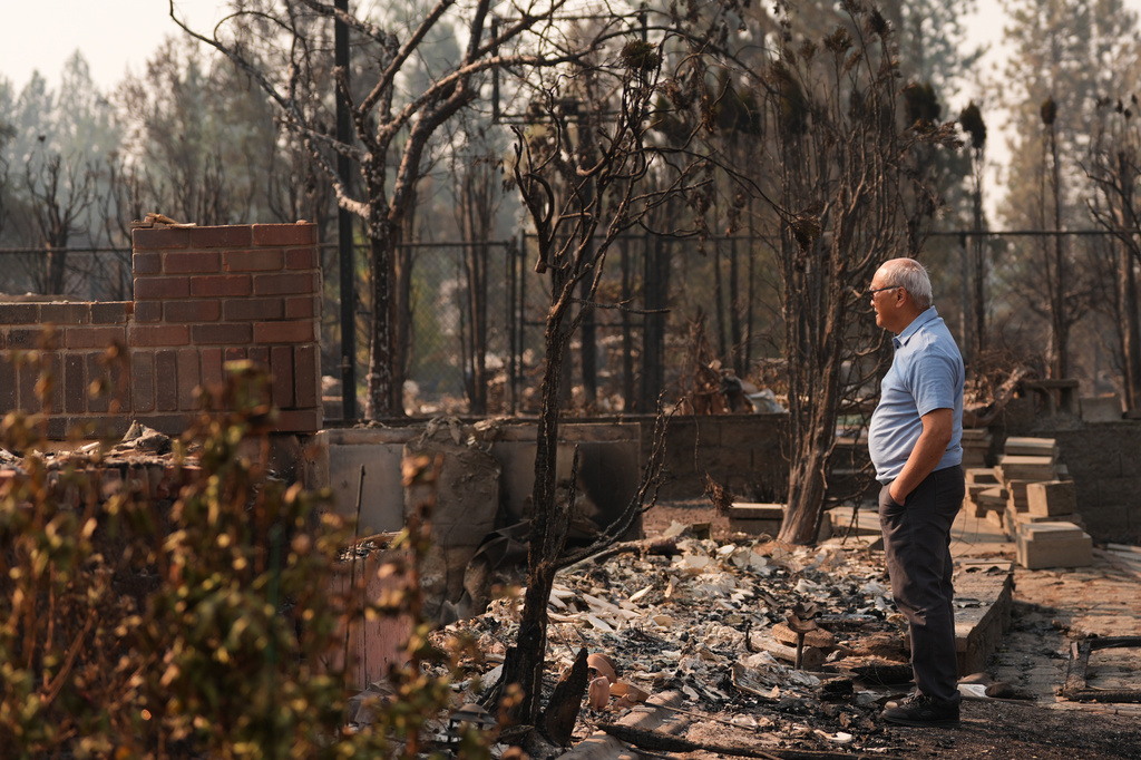 Daniel Sim, 76, views the remains of his destroyed house after a wildfire hit the northern part of Spokane, Wash., Monday, Aug. 3, 2026. (AP Photo/Lindsey Wasson)