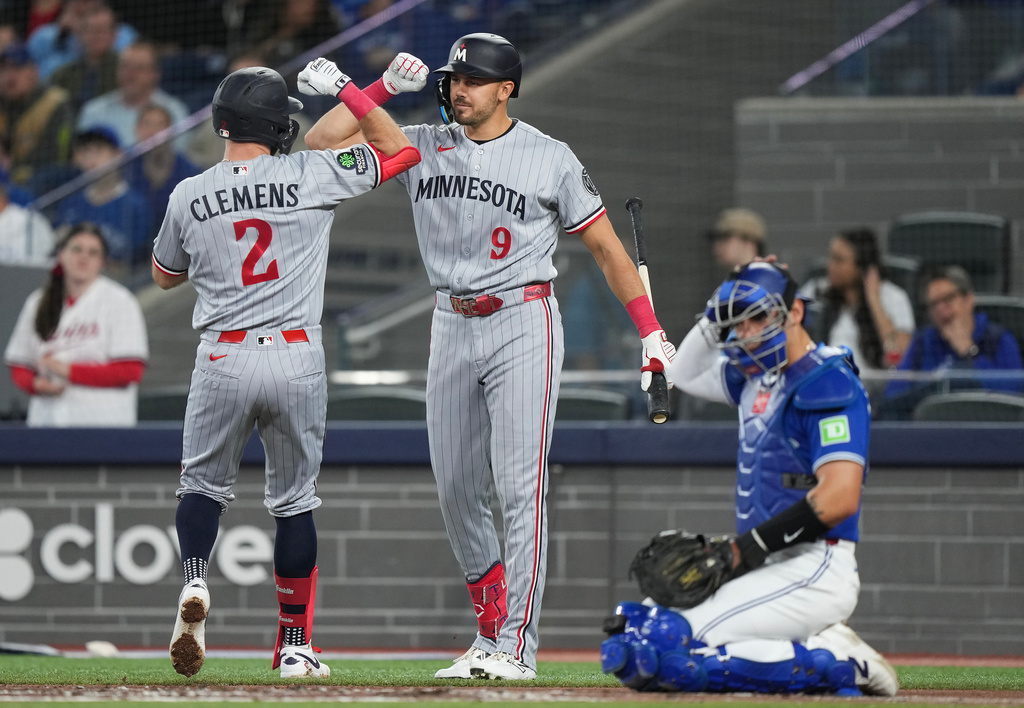 Minnesota Twins' Kody Clemens (2) celebrates with teammate Trevor Larnach (9) after hitting a solo home run during third-inning baseball game action against the Toronto Blue Jays in Toronto, Sunday, April 12, 2026. (Nathan Denette/The Canadian Press via AP)