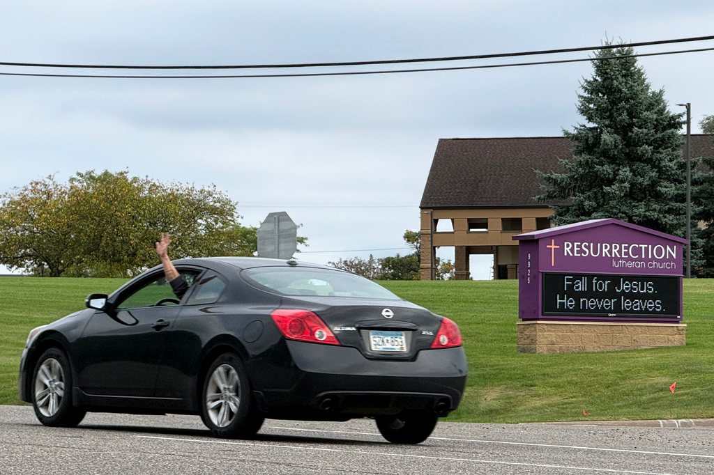 A driver waves while passing in front of Resurrection Lutheran Church and its church sign, featuring a seasonal pun, in Woodbury, Minn., on Sunday, Sept. 27, 2026. (AP Photo/Giovanna Dell'Orto)