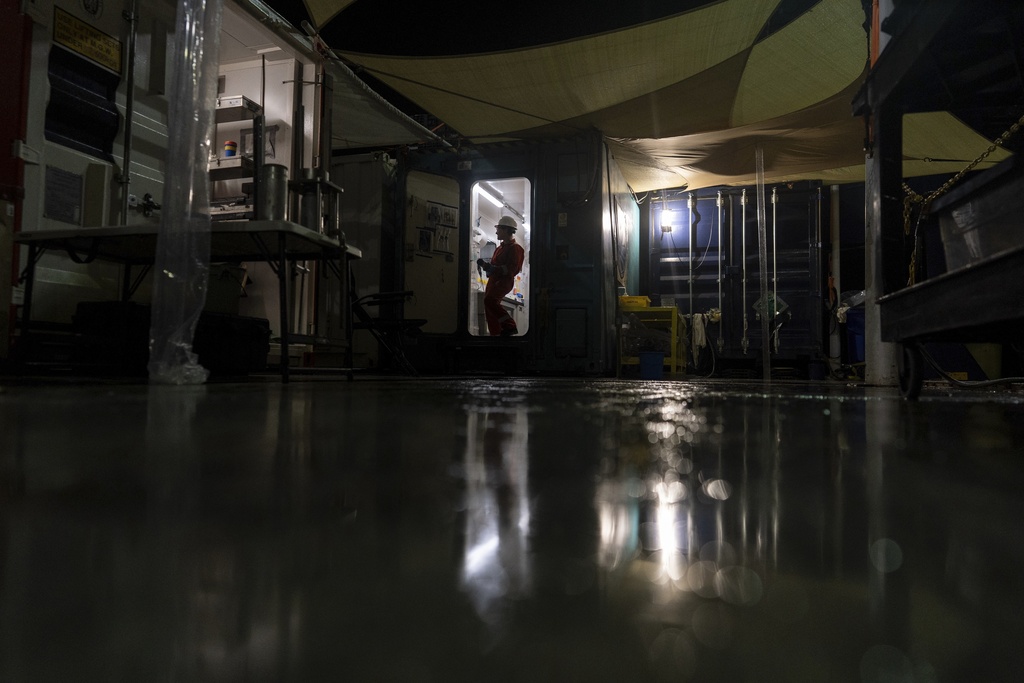 Expedition 501 researcher Patrizia Geprägs works to collect water samples from the cores in the curation container aboard the Liftboat Robert platform, in the North Atlantic, in the early morning hours, Sunday, July 20, 2025. (AP Photo/Carolyn Kaster)