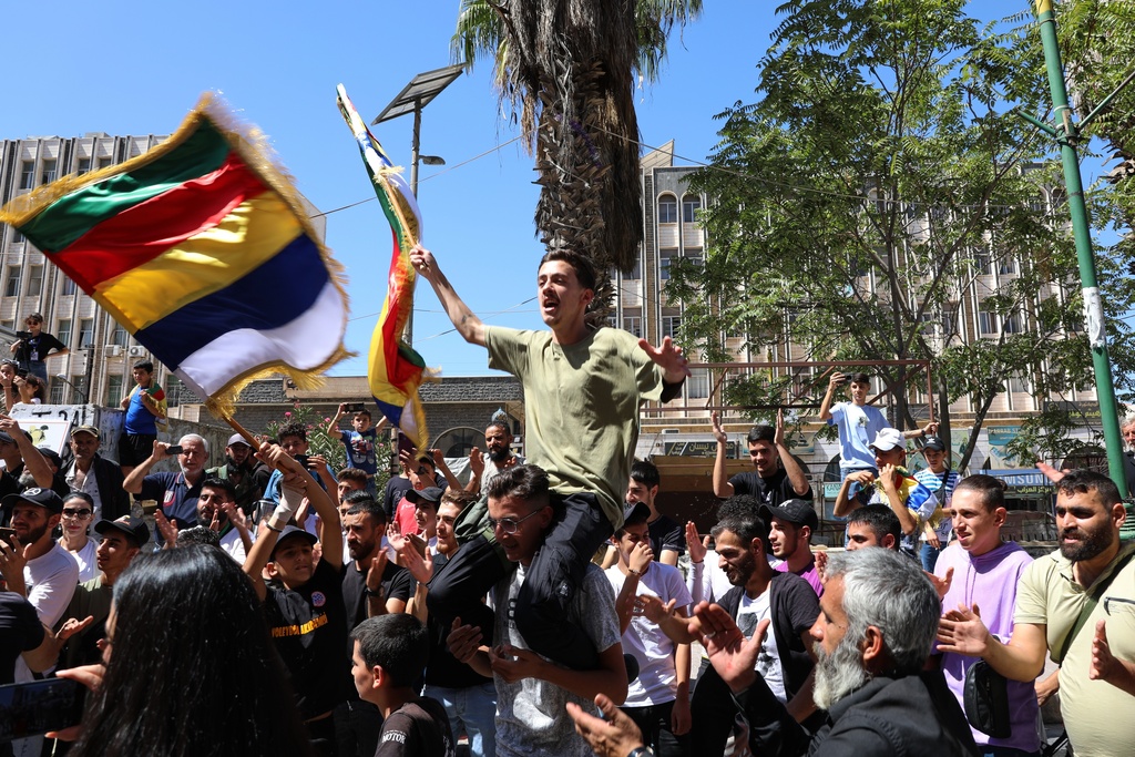 People chant slogans while waving the Druze flag during a weekly rally in Sweida, southern Syria, on Sept. 20, 2025. (AP Photo/Fahd Kiwan)