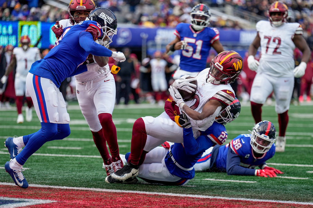 Washington Commanders running back Jacory Croskey-Merritt (22) is tackled by New York Giants cornerback Andru Phillips (22) as he crosses the goal line for a touchdown during the second quarter of an NFL football game, Sunday, Dec. 14, 2025, in East Rutherford, N.J. (AP Photo/Seth Wenig)