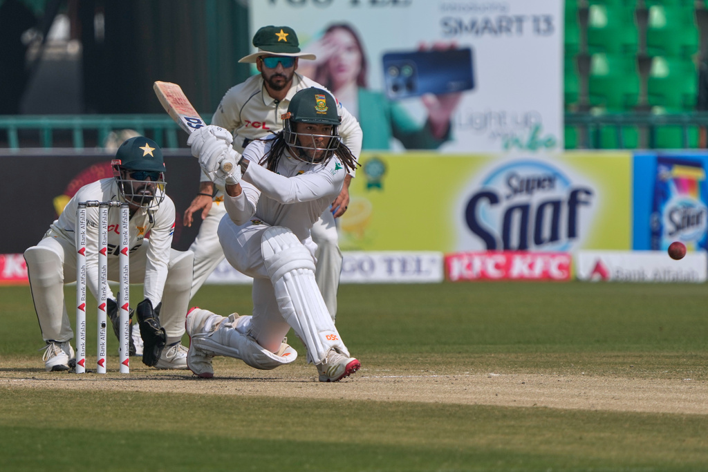 South Africa's Tony dy Zorzi, front, plays a shot, as Pakistan Mohammad Rizwan, left, and Salman Ali Agha watch during the third day of the first test cricket match between Pakistan and South Africa, in Lahore, Pakistan, Tuesday, Oct. 14, 2025. (AP Photo/K.M. Chaudary)