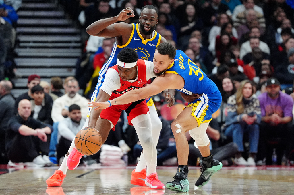 Toronto Raptors guard Ja'Kobe Walter, front left, tries to get the ball past Golden State Warriors guard Stephen Curry (30) and teammate Draymond Green, back left, during first-half NBA basketball game action in Toronto, Sunday, Dec. 28, 2025. (Frank Gunn/The Canadian Press via AP)