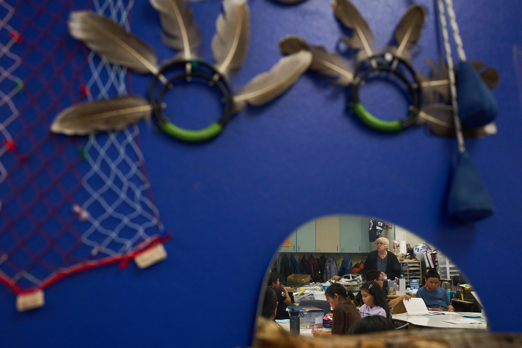 Students are seen reflected in a mirror on a wall full of traditional crafts as they spend half their day working in a Yup'ik language immersion program at College Gate Elementary, Thursday, Oct. 30, 2025, in Anchorage, Alaska. (AP Photo/Lindsey Wasson)