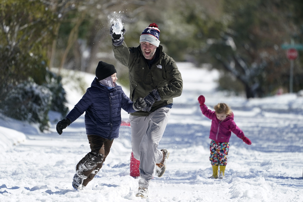 FILE - Craig Crow, center, throws snowballs as he plays in the snow with his children and neighbors, Feb. 15, 2021, in San Antonio. (AP Photo/Eric Gay, File)