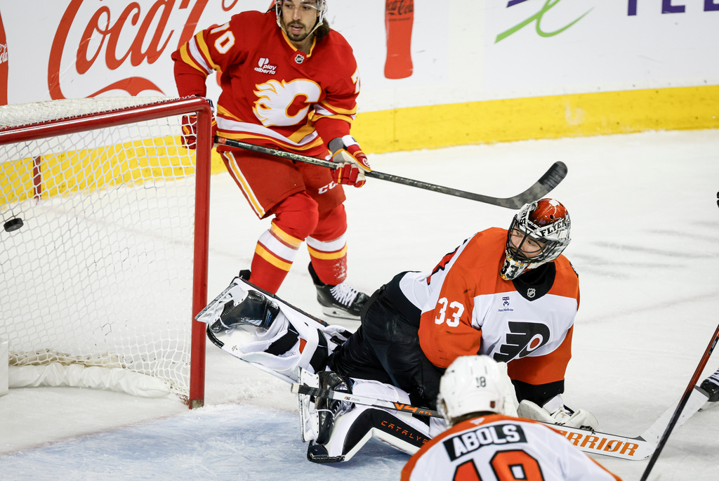 Philadelphia Flyers goalie Samuel Ersson, right, lets in a goal as Calgary Flames' Ryan Lomberg looks on during third period NHL hockey action in Calgary on Wednesday, Dec. 31, 2025. (Jeff McIntosh/The Canadian Press via AP)