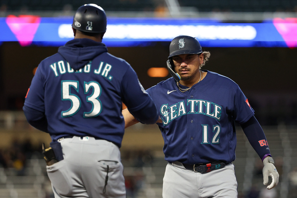 Seattle Mariners' Josh Naylor, right, celebrates his RBI single with first base coach Eric Young Jr. during the sixth inning of a baseball game against the Minnesota Twins, Tuesday, April 28, 2026, in Minneapolis. (AP Photo/Matt Krohn)