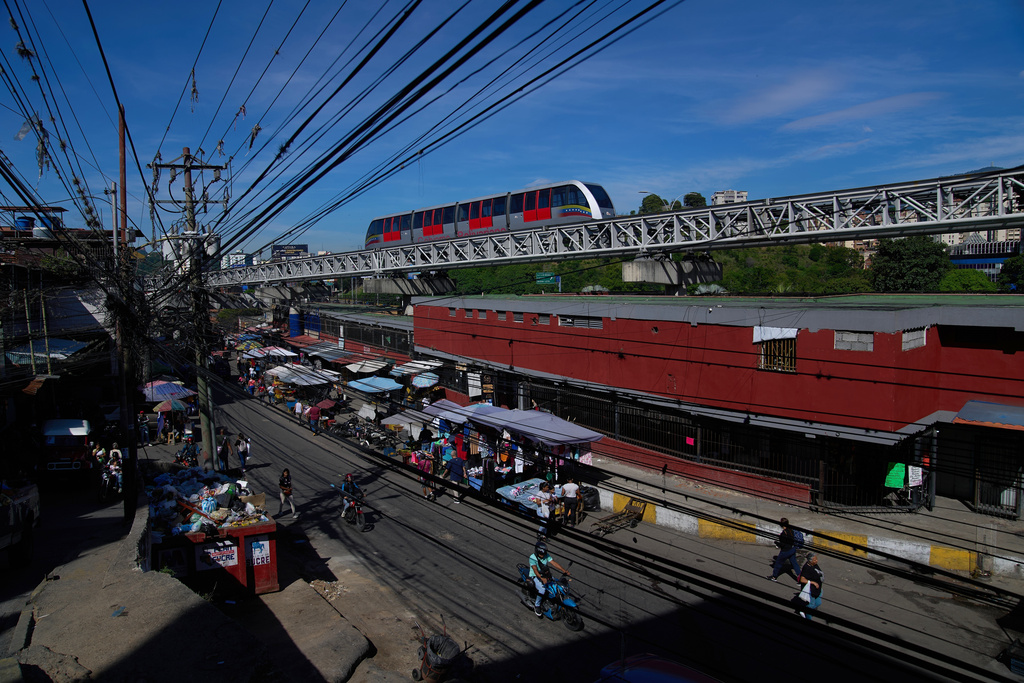 People walk past a street market below a metro line in Caracas, Venezuela, Thursday, Oct. 16, 2025. (AP Photo/Ariana Cubillos)