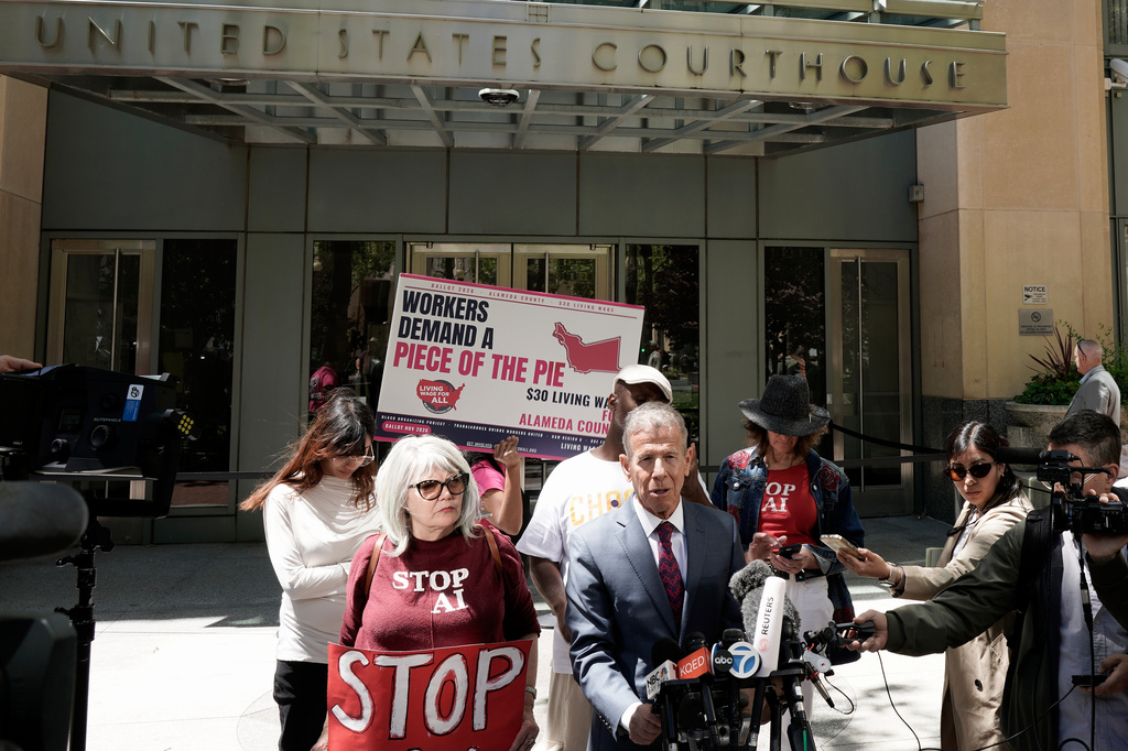 Marc Toberoff, attorney for Elon Musk, bottom middle, speaks to reporters outside the U.S. District Court, Monday, May 18, 2026, in Oakland, Calif. (AP Photo/Nathan Weyland)