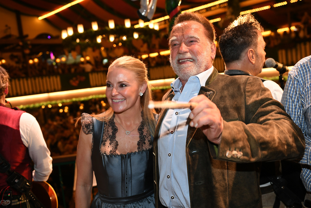 Arnold Schwarzenegger and his partner, Heather Milligan stand on stage during the 190th Oktoberfest on Friday, Sept. 26, 2025, in Munich, Germany. (Felix Hörhager/dpa via AP)