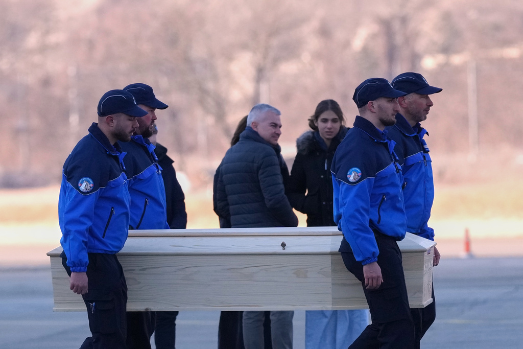Police officers carry a coffin with a body of one of six Italians at the Military Airport in Sion, Swiss Alps, Switzerland, Monday, Jan. 5, 2026, following a devastating fire left dead and injured in a bar in Crans-Montana during the New Year's celebrations. (AP Photo/Antonio Calanni)