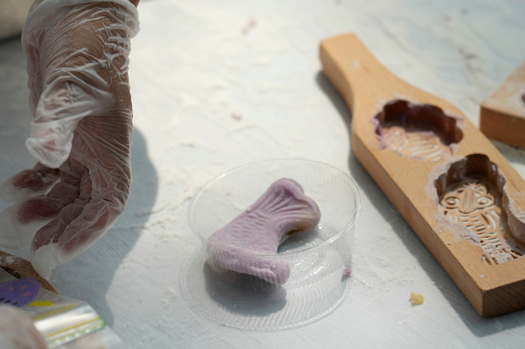 Participants create qiaoguo, a pastry made by pressing dough into decorative molds, during a festival to celebrate Qixi at the Beijing Folk Custom Museum in Beijing, Wednesday, Aug. 19, 2026. (AP Photo/Achmad Ibrahim)